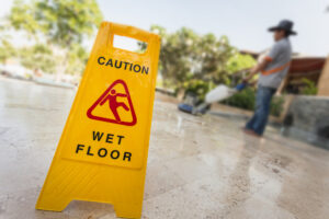 Trip and Fall Lawyer Metairie, LA - Yellow caution sign and blur of man doing floor polishing
